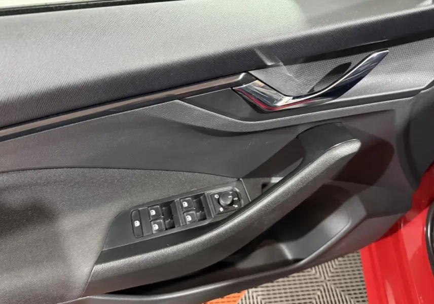 Gros plan sur la porte côté conducteur noire avec commandes électriques sur un Skoda Kamiq rouge 2024.