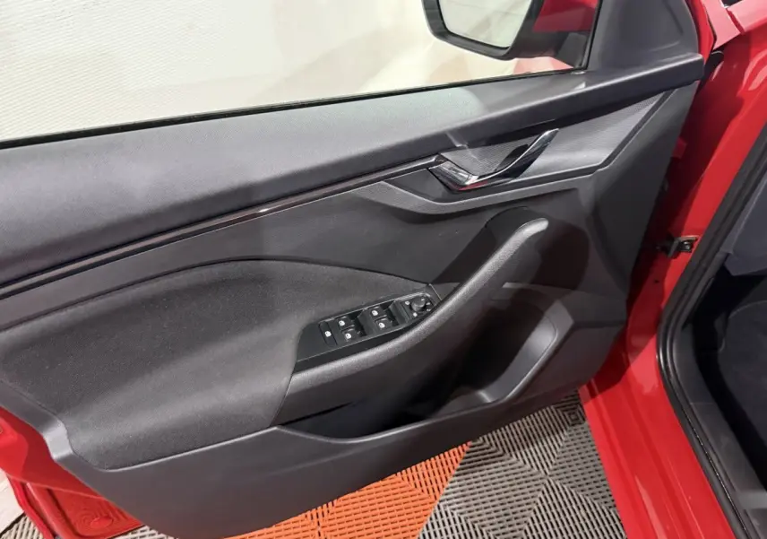 Gros plan sur la porte avant gauche rouge du Skoda Kamiq 2024, avec commandes électriques des vitres et poignée intégrée.