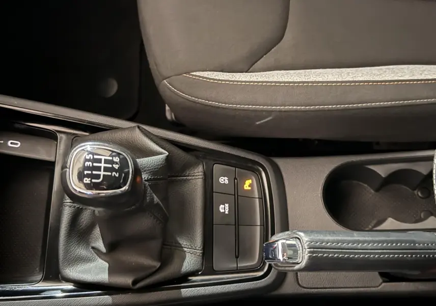 Gros plan sur la commande de boîte manuelle et frein à main cuir dans l’habitacle du Skoda Kamiq rouge 2024.