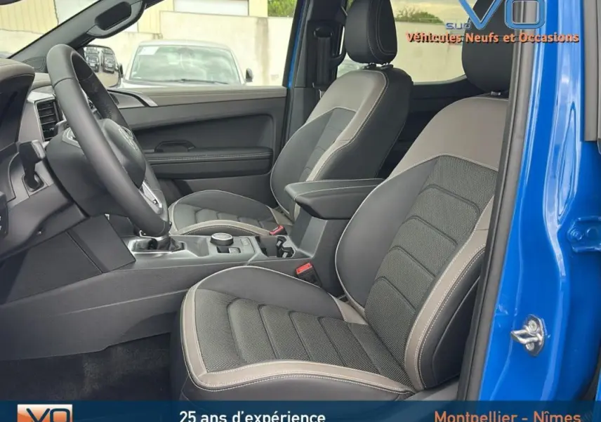 Vue intérieure côté droit du Volkswagen Amarok Simple Cabine bleu 2025, sièges en cuir avec accoudoir central visible.