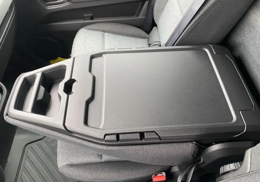 Vue rapprochée de la banquette passager grise avec bureau mobile intégré dans un Renault Master blanc 2025.