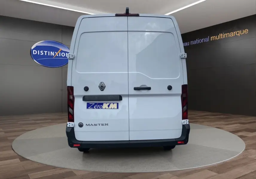 Vue arrière d’un Renault Master blanc avec portes arrière tôlées et logo noir sur fond clair en showroom.