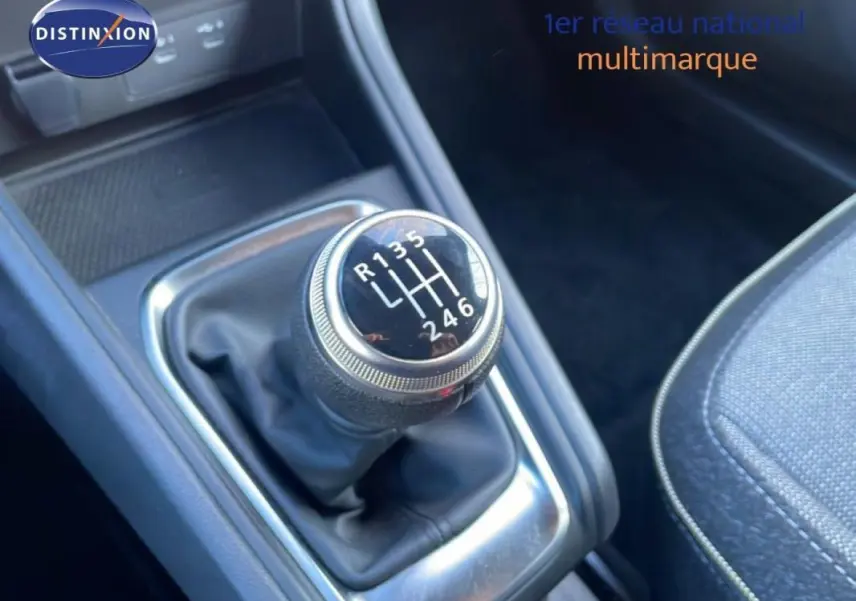 Gros plan sur le levier de vitesses manuel noir du Renault Captur rouge 2025, avec coutures apparentes sur la console.