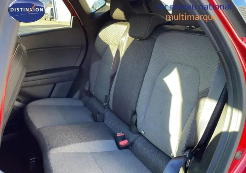 Vue intérieure sur les sièges arrière gris du Renault Captur rouge, avec ceinture de sécurité et porte arrière ouverte.