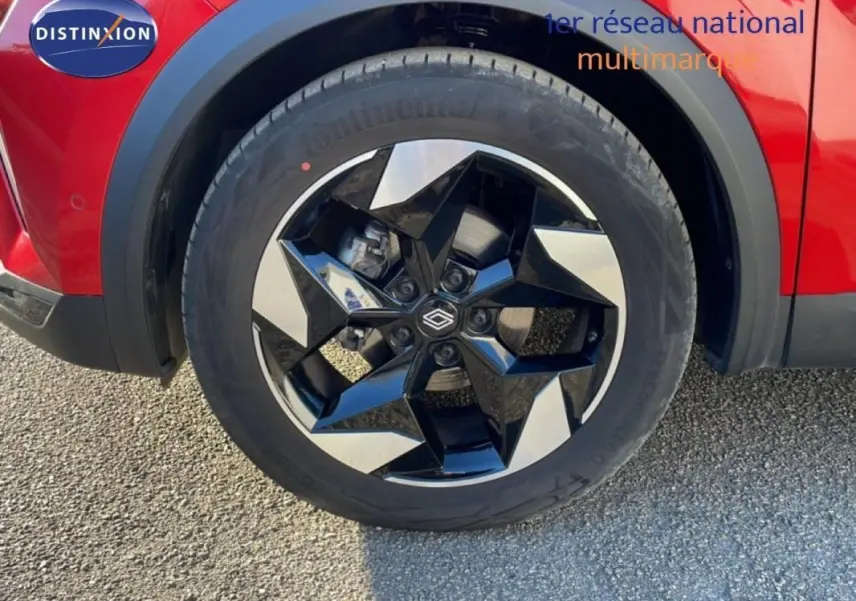 Gros plan sur la jante aluminium noire et argent du côté avant gauche du Renault Captur rouge 2025.