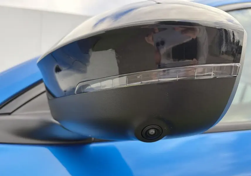 Gros plan sur le rétroviseur droit noir brillant avec caméra intégrée d’un Renault Rafale Summit Blue.