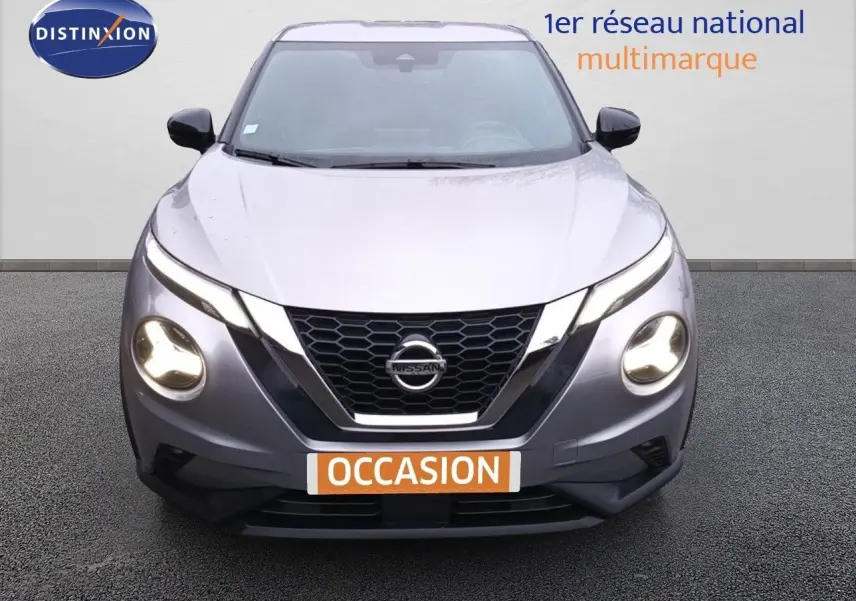 Vue frontale d'un Nissan Juke gris platine métal de 2020 avec phares allumés et calandre en nid d'abeille.