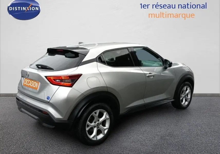 Vue 3/4 arrière droite d'un Nissan Juke gris platine métallisé avec jantes alliage et feux arrière allumés.