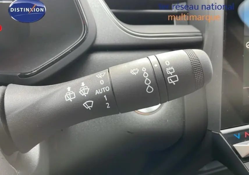 Gros plan sur la commande d’essuie-glace du Renault Captur gris 2025, avec tableau de bord et écran tactile en arrière-plan.