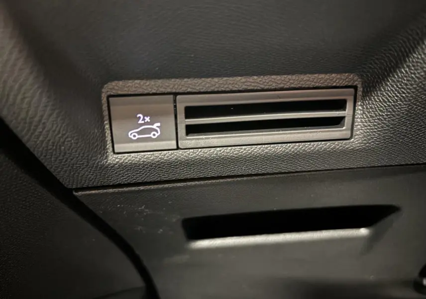 Gros plan sur le bouton d'ouverture du hayon électrique dans l'habitacle noir du Peugeot 3008 Gris Artense.