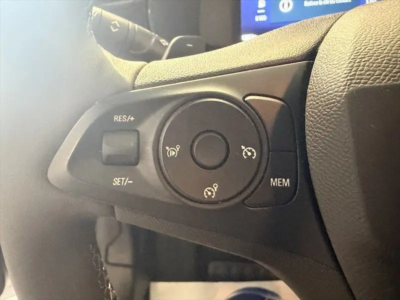 Gros plan sur les commandes de régulateur de vitesse au volant d'une Opel Corsa gris 1.2 Turbo 2025, côté gauche.