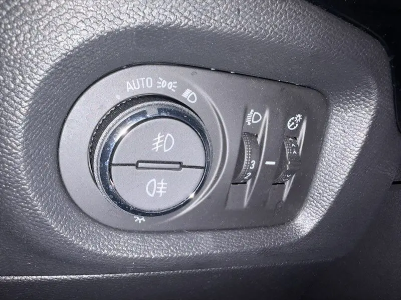 Gros plan sur la commande des phares de l’Opel Corsa 1.2 Turbo 100 Edition BVA8 gris, intérieur côté conducteur.