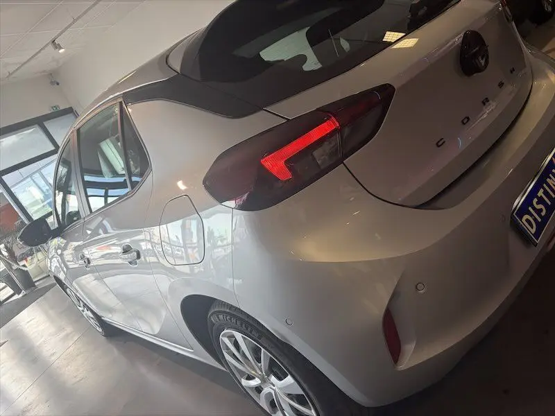 Vue 3/4 arrière droite d'une Opel Corsa gris clair 2025 avec feux arrière allumés et jantes alliage en showroom.