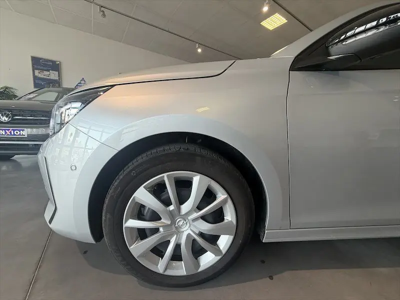 Gros plan sur la roue avant gauche d'une Opel Corsa gris 2025, vue de profil dans un showroom lumineux.
