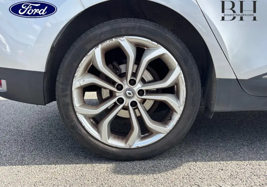 Gros plan sur la roue arrière droite d'un Renault Grand Scénic gris platine avec jante alliage à motif moderne.