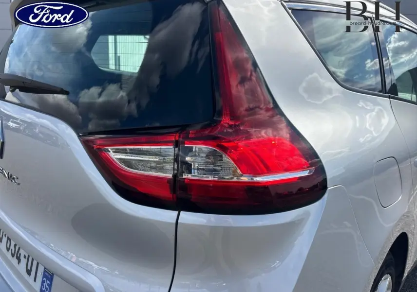 Vue arrière droite du Renault Grand Scénic gris platine, mettant en valeur le feu arrière et la lunette teintée.