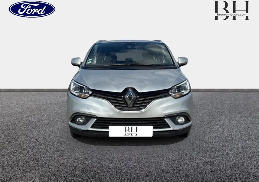 Renault Grand Scenic gris platine vue de face, avec calandre noire et phares LED allumés sur fond neutre.