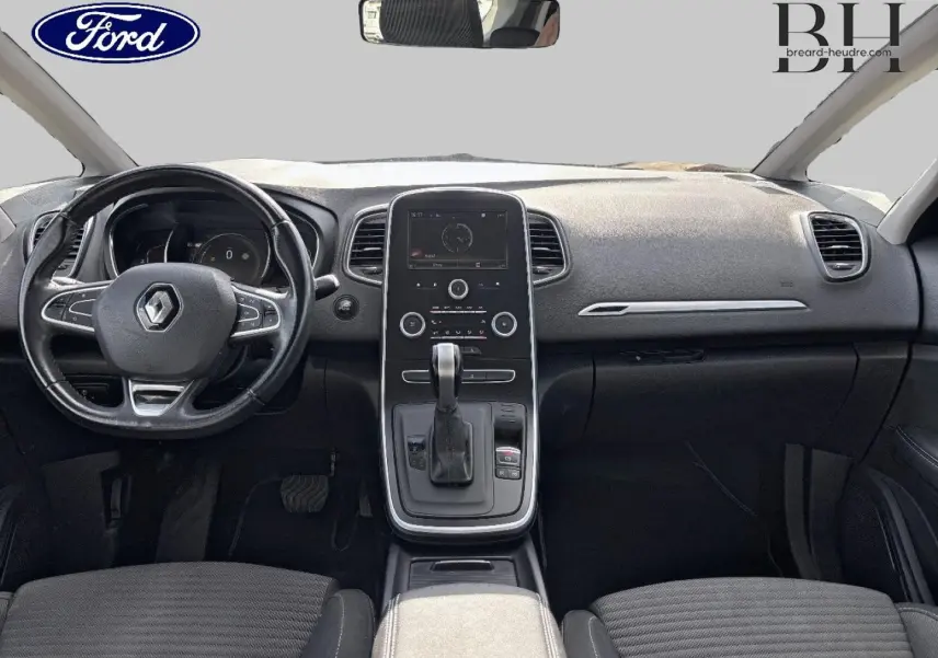 Vue intérieure avant du tableau de bord et console centrale du Renault Grand Scenic gris avec volant cuir et écran tactile.