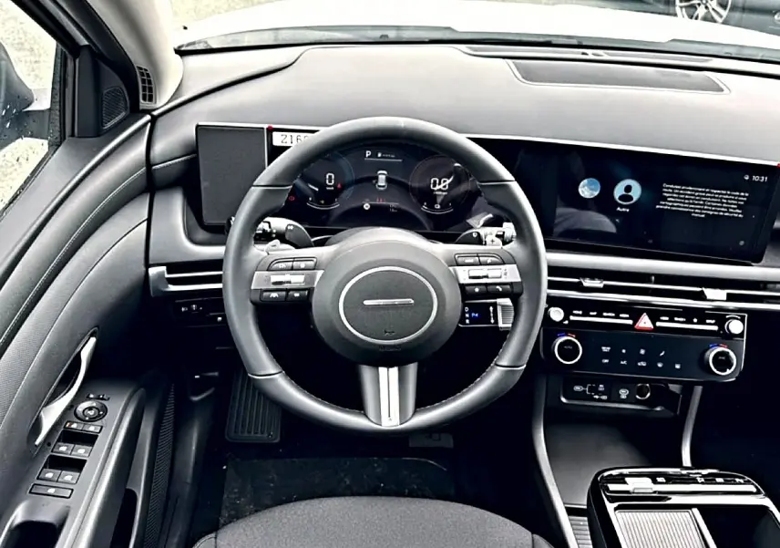 Vue intérieure frontale du tableau de bord du Hyundai Tucson 2026, volant cuir multifonction et écran digital large.