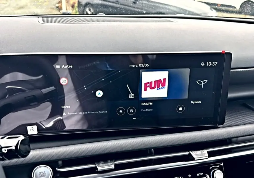 Vue rapprochée de l'écran tactile central du tableau de bord du Hyundai Tucson blanc, affichant la radio et la navigation.