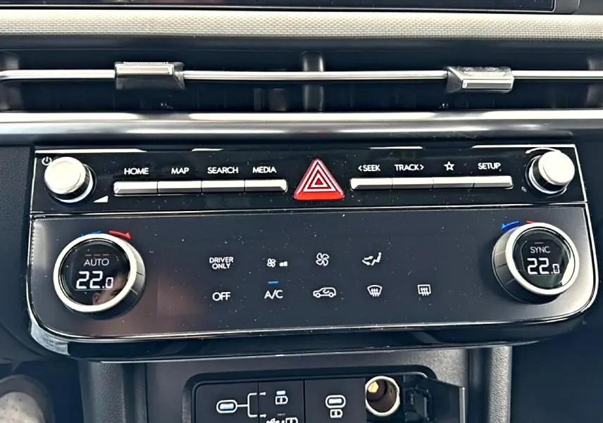 Vue rapprochée de la console centrale du Hyundai Tucson 2026 hybride, avec commandes climatisation digitale à 22°C.