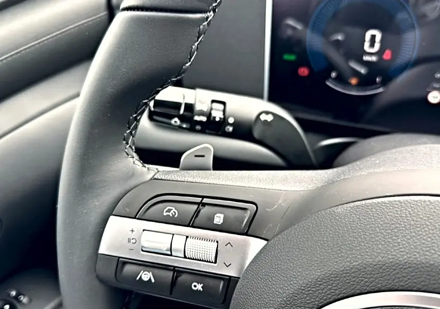 Gros plan sur le volant cuir multifonction du Hyundai Tucson 2026, avec commandes intégrées et tableau de bord numérique.