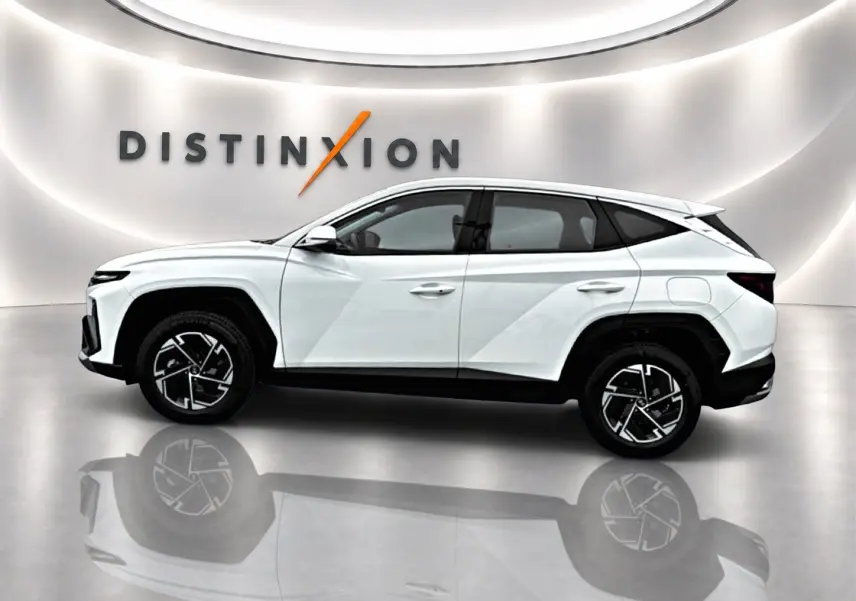 Vue de profil côté gauche du Hyundai Tucson blanc 2026 avec jantes alliage 17 pouces dans un showroom lumineux.
