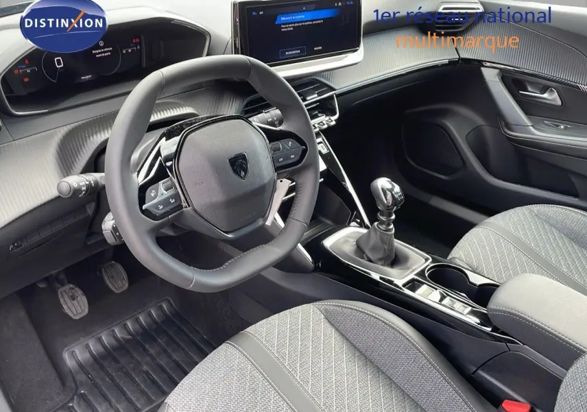 Intérieur du Peugeot 2008 2025 côté conducteur, volant compact, tableau de bord numérique et sellerie tissu gris.