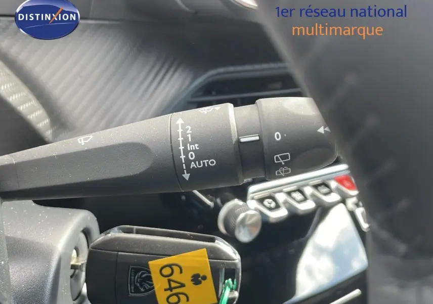 Gros plan sur la commande d'essuie-glace et la clé insérée dans le contact d'un Peugeot 2008 noir Perla Metal, intérieur moderne.