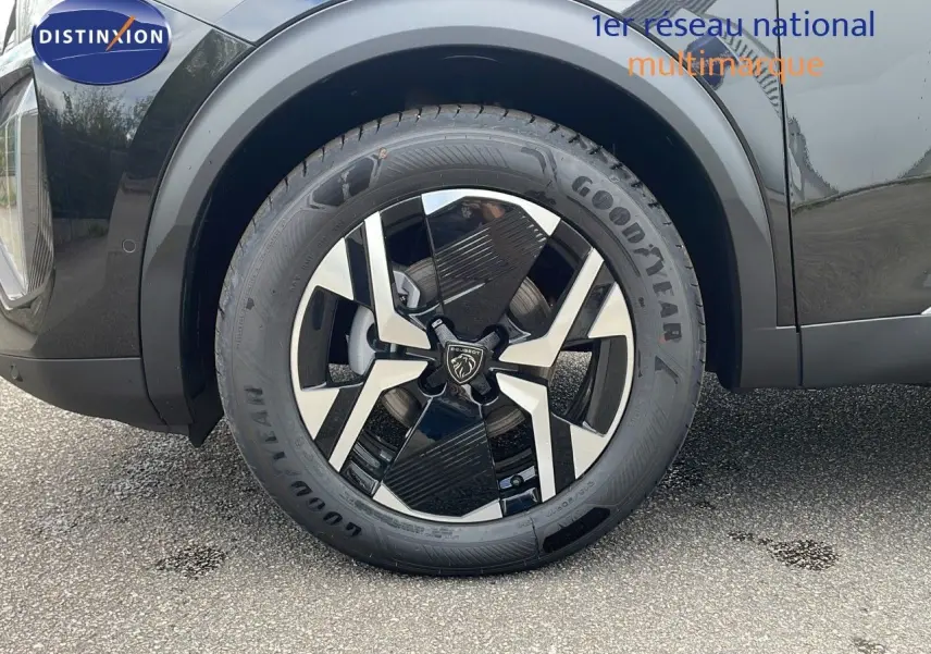 Gros plan sur la roue avant gauche du Peugeot 2008 noir Perla Metal avec jante alliage bicolore et pneu Goodyear.