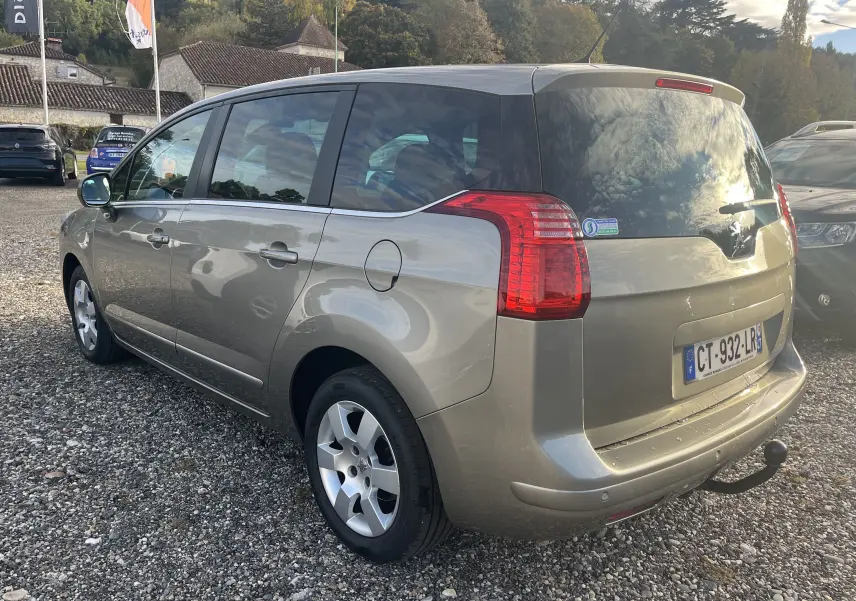 Peugeot 5008 gris métallisé vue 3/4 arrière droit, avec hayon fermé et attelage de remorque visible.