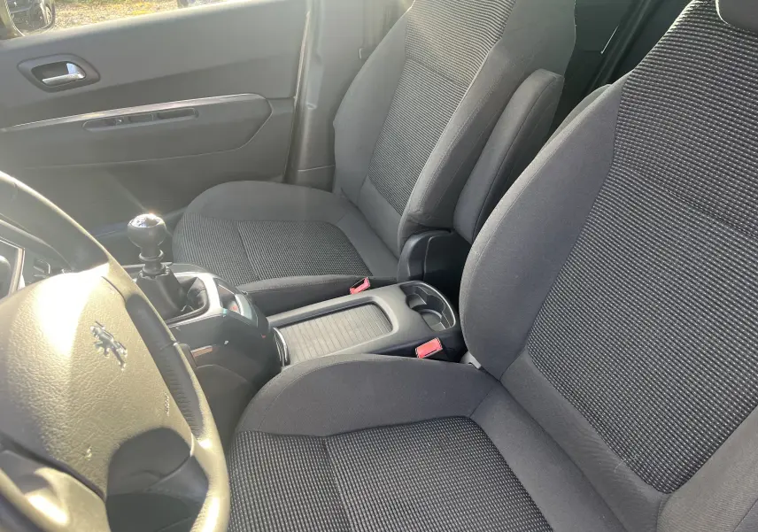 Intérieur avant du Peugeot 5008 2013, sièges tissu gris et levier de vitesse manuel visible côté gauche.