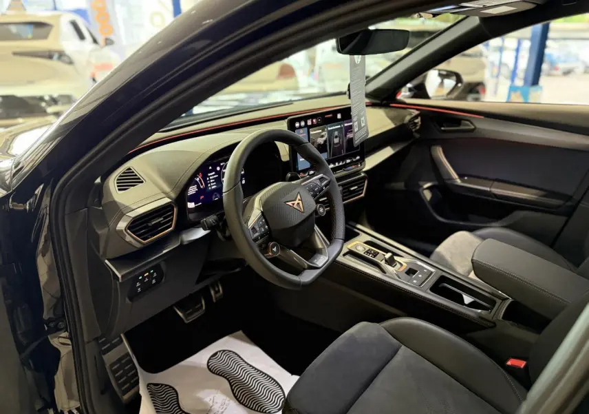 Intérieur du CUPRA Formentor 2025 vu côté conducteur, avec sièges suédine noir et tableau de bord moderne à écran tactile.