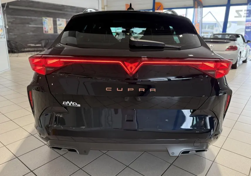 Vue arrière d'une CUPRA Formentor noire Night avec feux arrière en bandeau lumineux et double sortie d'échappement.