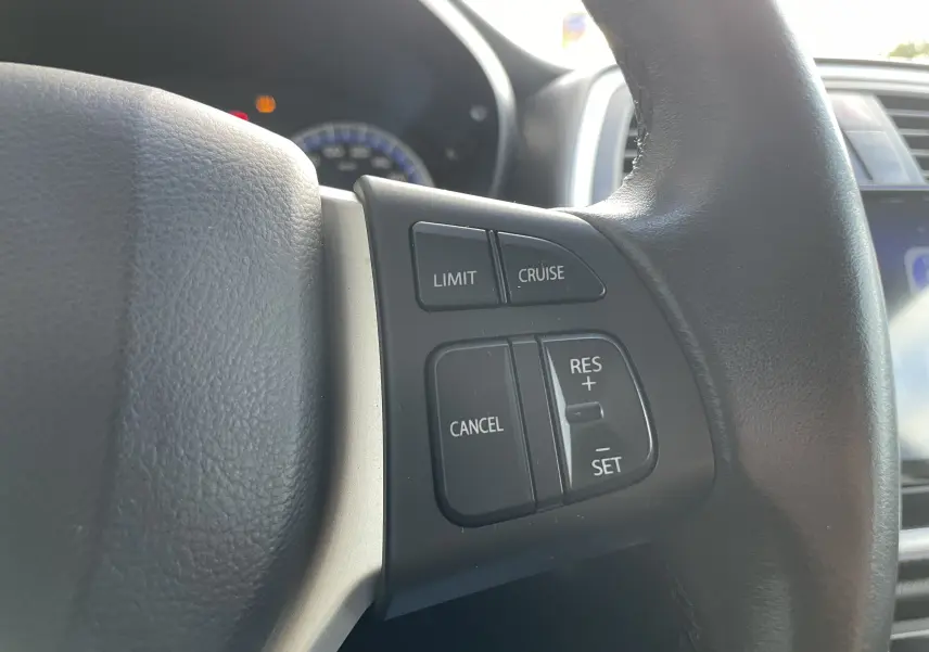 Gros plan sur les commandes de régulateur de vitesse au volant noir du Suzuki SX4 S-Cross gris 2016.