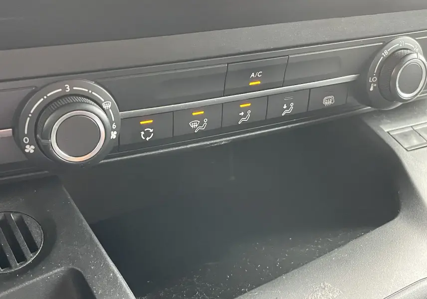 Panneau de commande de climatisation avec boutons allumés dans l'habitacle gris noir du Citroën Berlingo blanc 2018.