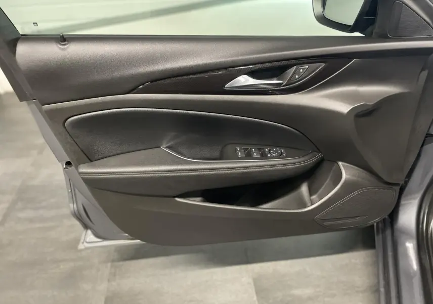 Panneau de porte côté gauche noir avec commandes électriques sur Opel Insignia Grand Sport gris clair, vue intérieure.