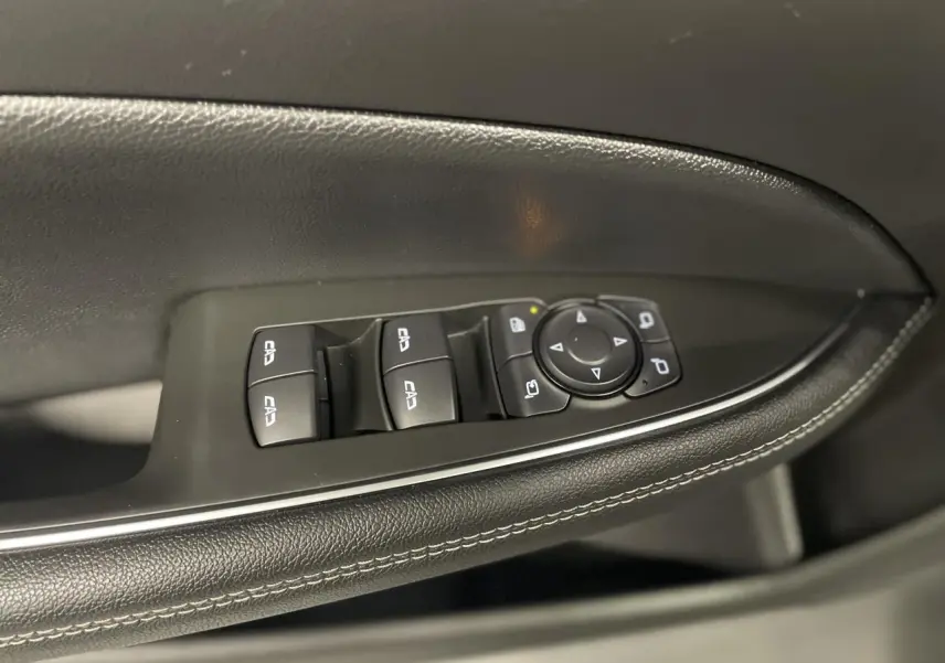 Gros plan sur la commande des vitres et rétroviseurs côté conducteur en cuir noir avec surpiqûres blanches dans une Opel Insignia Grand Sport 2021.