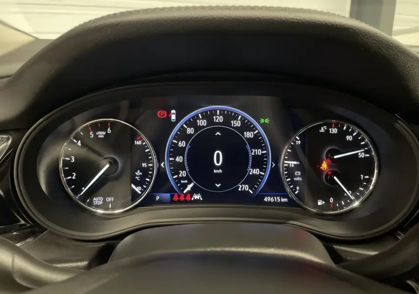Vue rapprochée du tableau de bord numérique de l'Opel Insignia Grand Sport gris clair, affichant 0 km/h et 49 615 km.