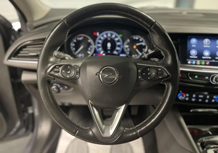 Volant en cuir multifonctions de l'Opel Insignia Grand Sport 2021, avec tableau de bord et écran tactile en arrière-plan.