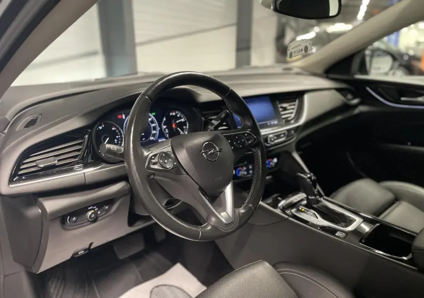 Intérieur noir de l’Opel Insignia Grand Sport 2021, vue côté conducteur sur le volant cuir multifonctions et console centrale.