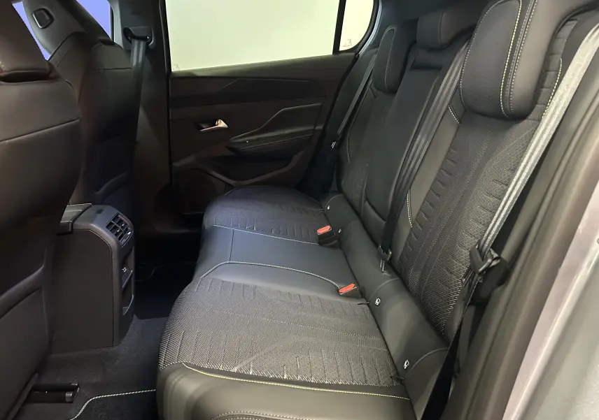 Vue intérieure arrière côté droit de la Peugeot 308 III Ph.2 GT avec sièges tissu et cuir noirs à surpiqûres vertes.