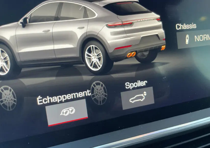 Vue arrière droite du Porsche Cayenne Coupé hybride noir, mettant en valeur les doubles sorties d’échappement sport oranges.