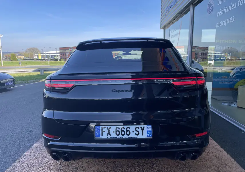 Vue arrière d'un Porsche Cayenne Coupé E-Hybrid noir, avec feux LED et double sortie d'échappement sport visible.