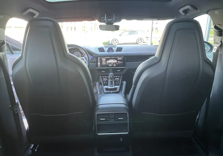 Vue intérieure arrière du Porsche Cayenne Coupé e-Hybrid noir, mettant en valeur les sièges sport en cuir et le toit panoramique.