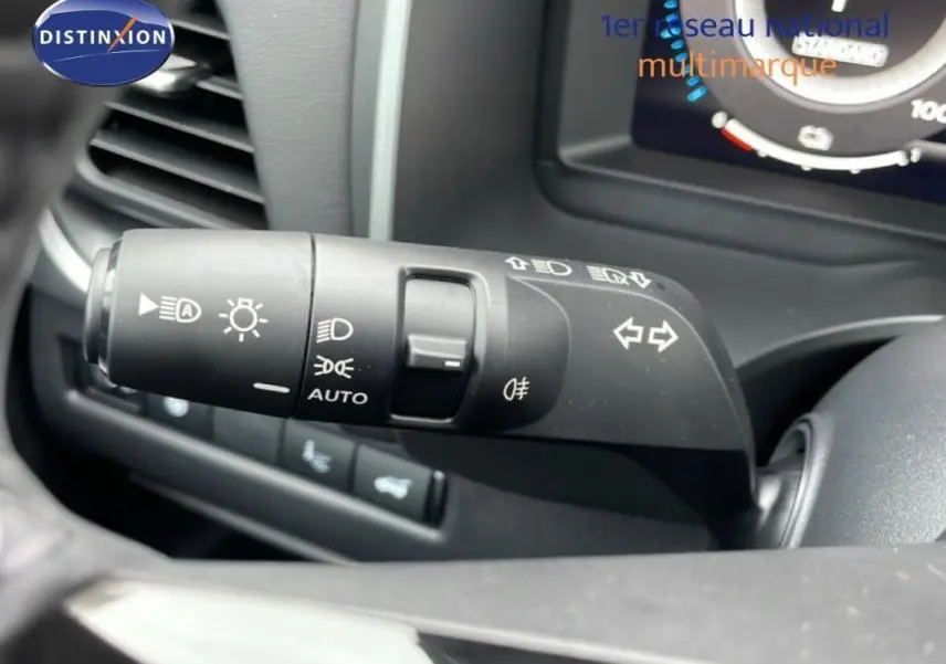 Gros plan sur la commande des feux et clignotants du Nissan Qashqai blanc 2025, intérieur noir.