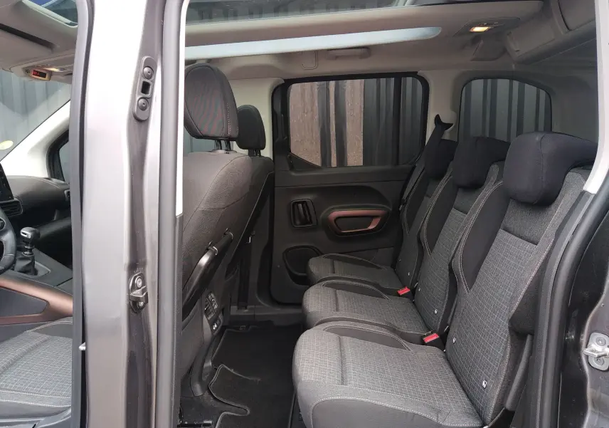 Intérieur du Peugeot Rifter gris platinium 2022 vu côté droit, montrant les sièges arrière en tissu noir à motifs.