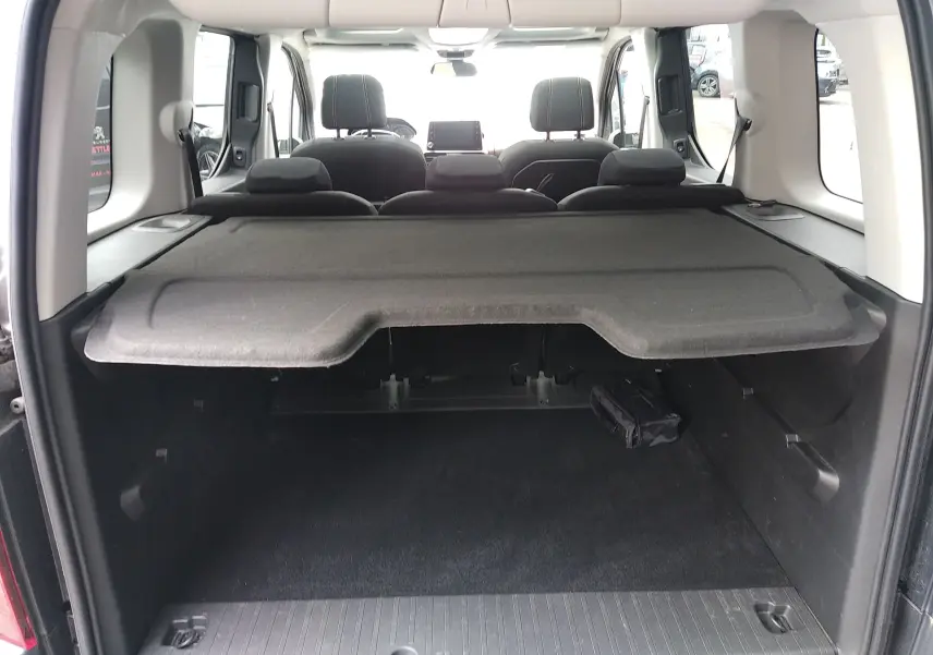 Vue arrière du coffre du Peugeot Rifter gris platinium 2022, avec cache-bagages et sièges arrière visibles.