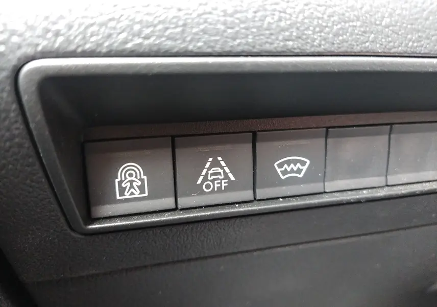 Gros plan sur les boutons de commande du tableau de bord du Peugeot Rifter gris platinium, avec symboles d’alerte et assistance.