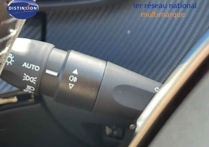 Gros plan sur la commande des phares et clignotants dans l'habitacle d'un Peugeot 2008 bleu Vertigo Metal 2024.